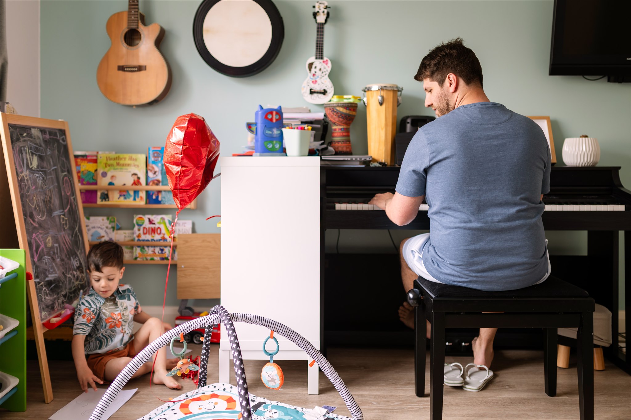 a family home at a photo session, father playing the piano for his son