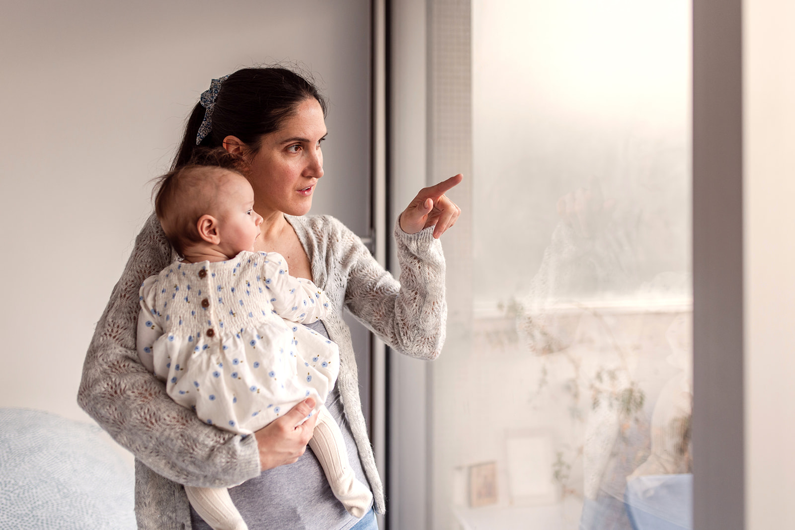 mother looking outside the window with her baby