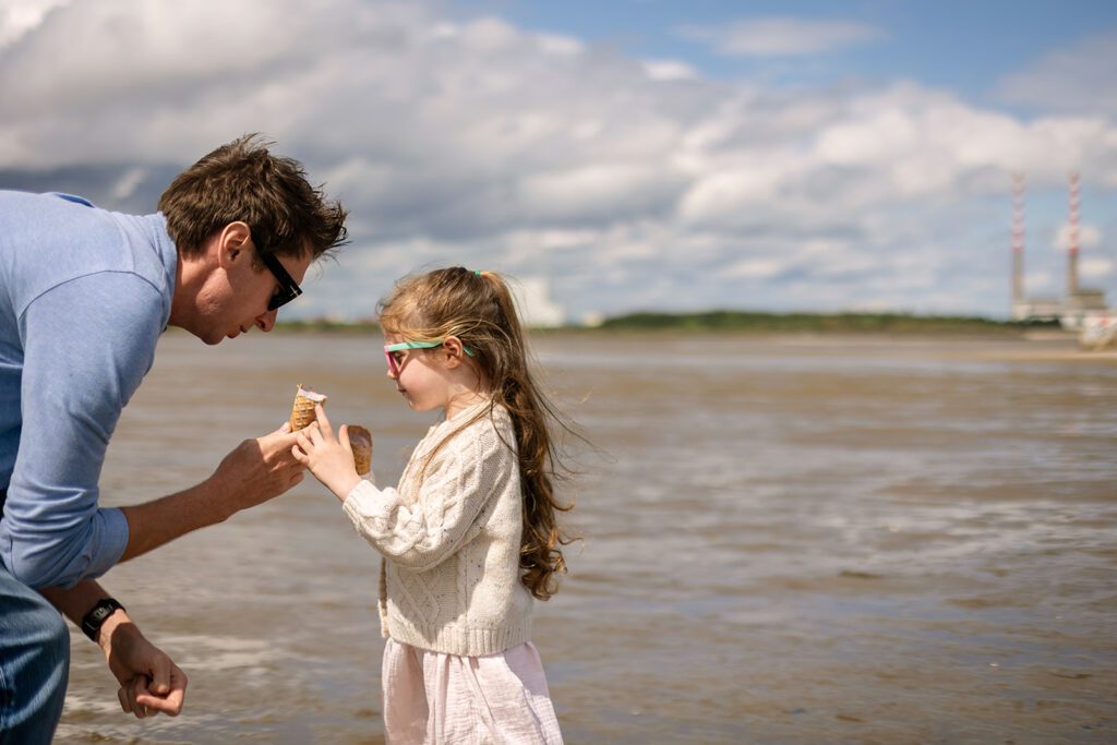 dad playing with his little girl on the beach during a photoshoot with a Family Photographer in Sandymount