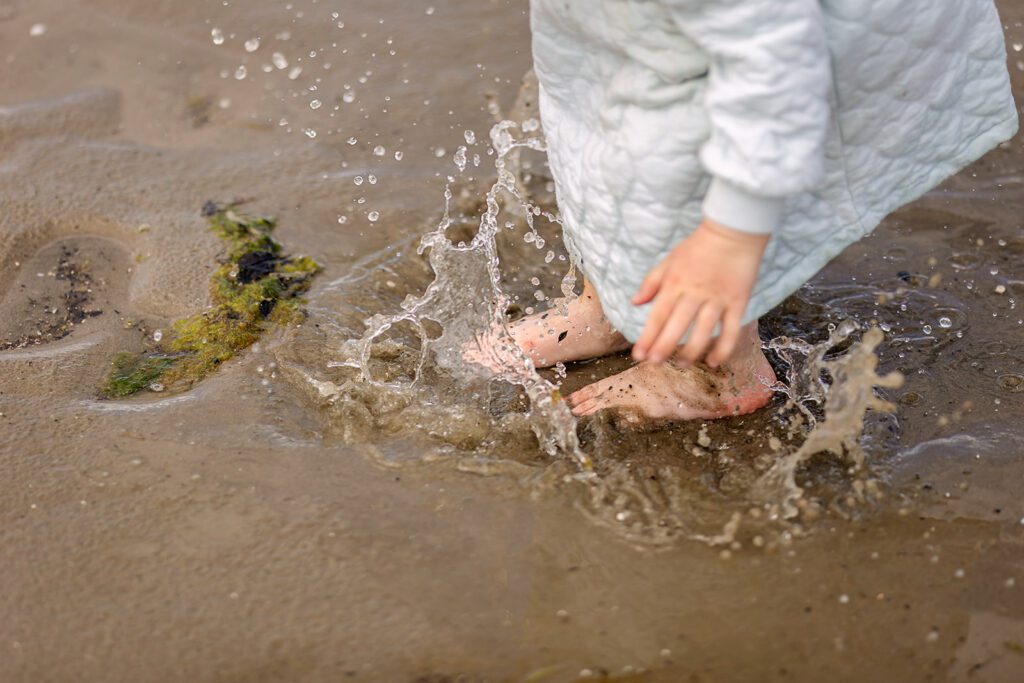 little girl jumping in a puddle at the beach