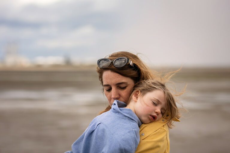 little girl sleeping in her mum's arms at the Sandymount beach