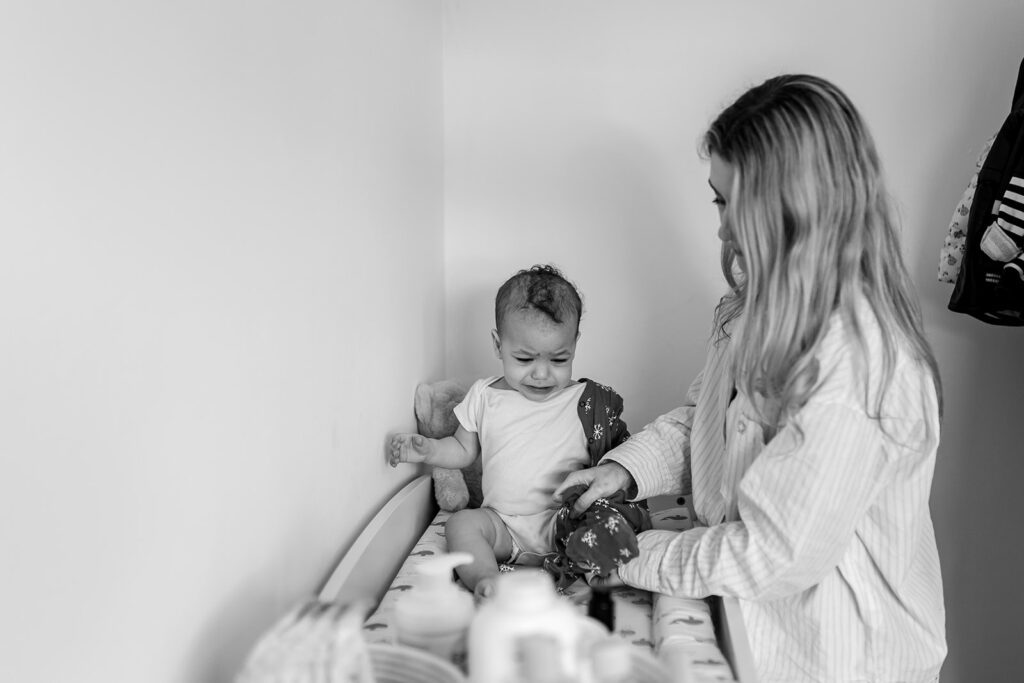 mom dressing her baby after nap at home for Unposed family photos