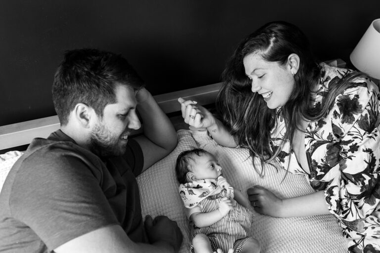 mom, dad and newborn smiling and cuddling during a documentary family photo session