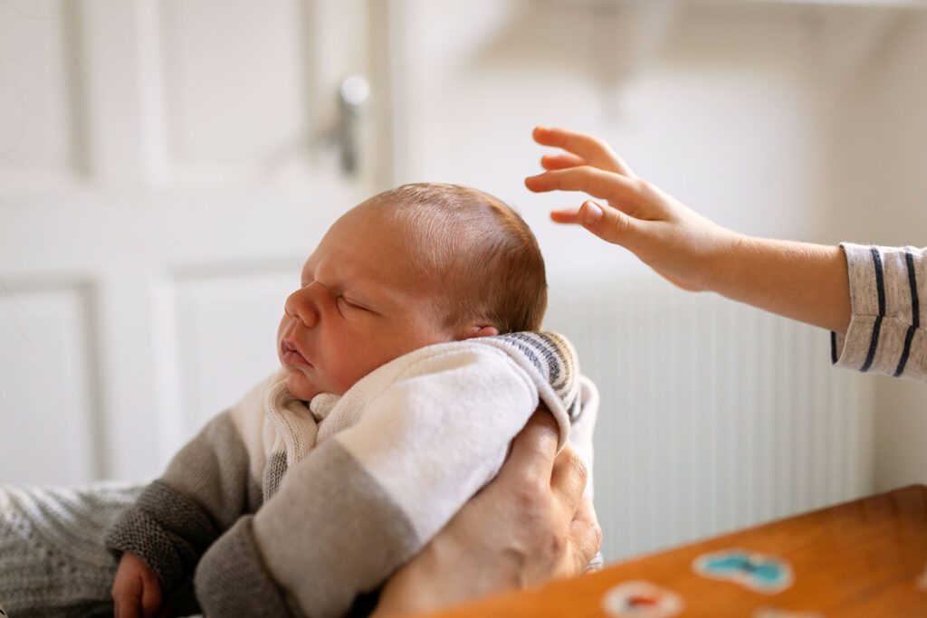 sibling reaching for his newborn baby brother