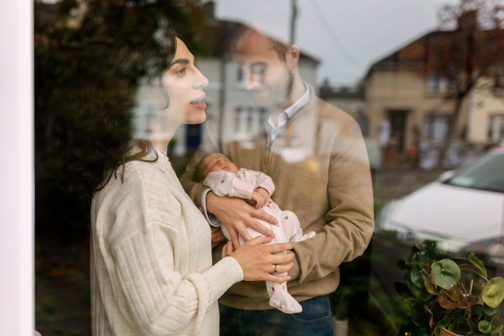 family with newborn looking out the window at home