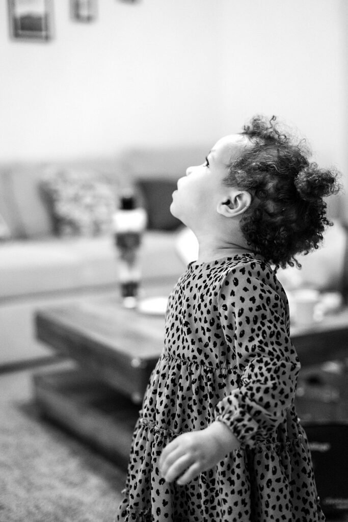 little girl watching her mom set up the christmas tree during a christmas family photo session at home