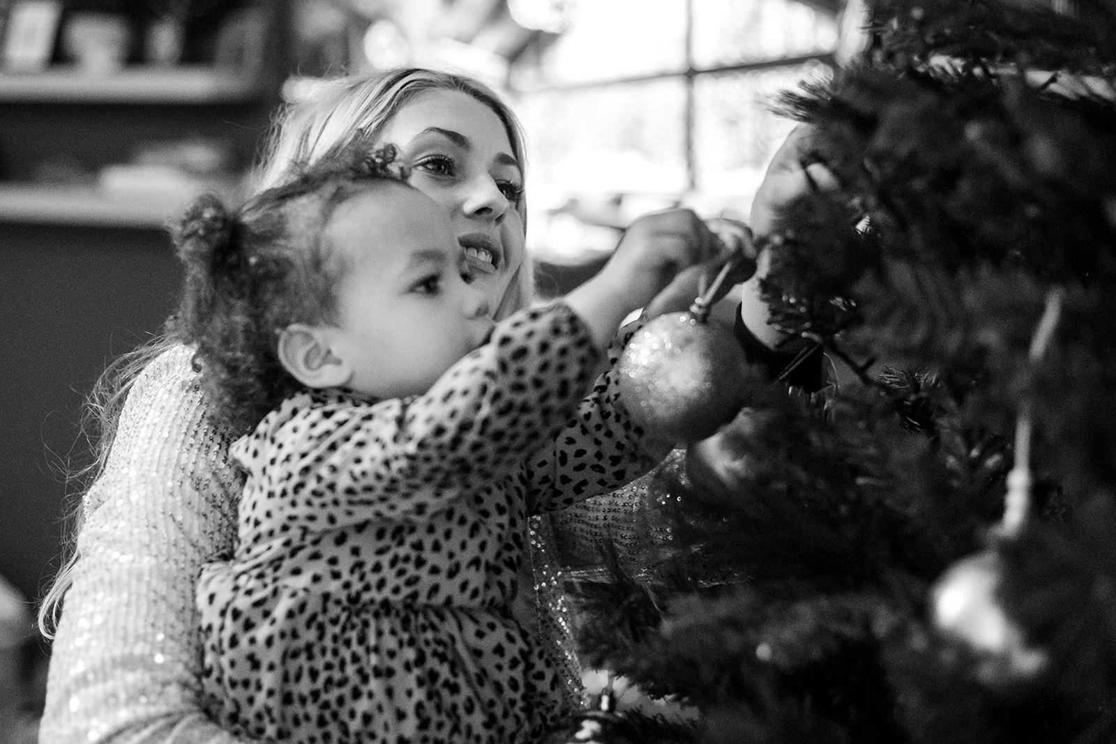 little girl decorating the christmas tree with her mom at home in Dublin