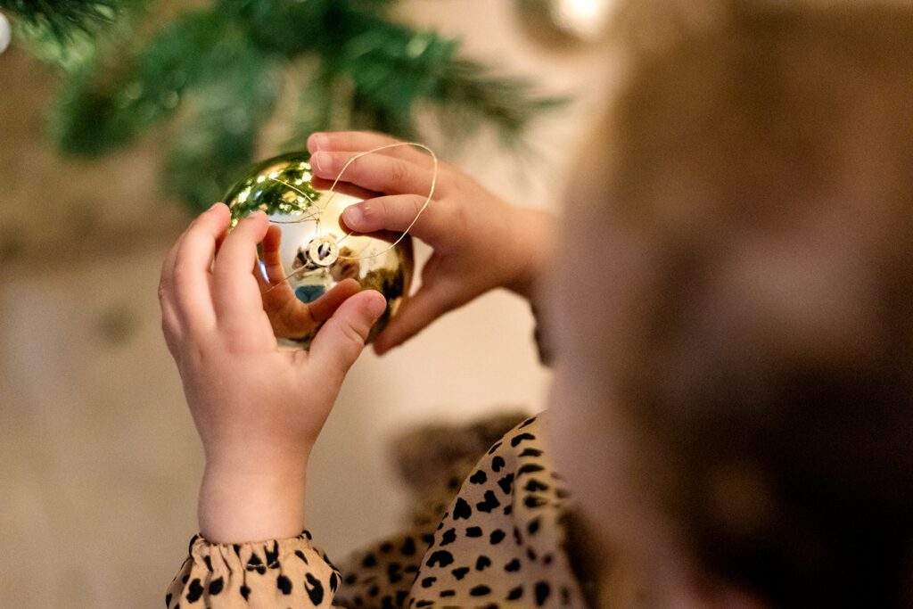 toddler watching her reflection in christmas baubble