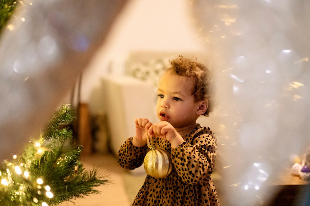 toddler decorating the lit up christmas tree at home in Dublin