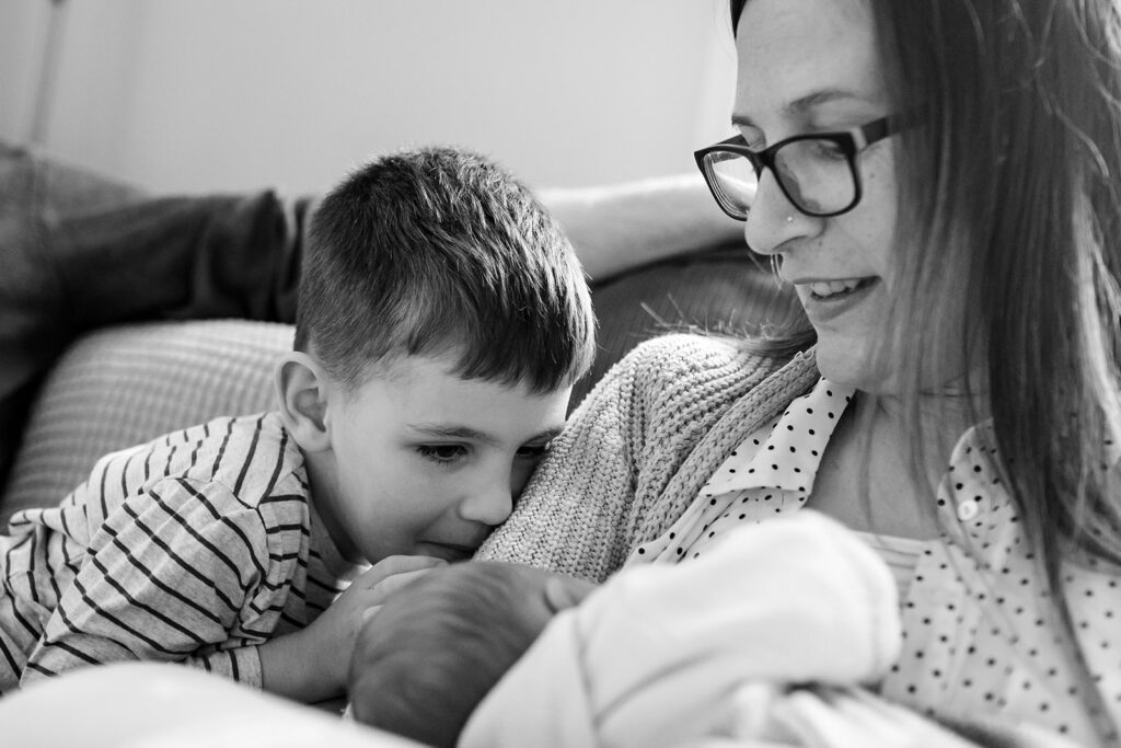 sibling gazing at his newborn brother breastfeeding