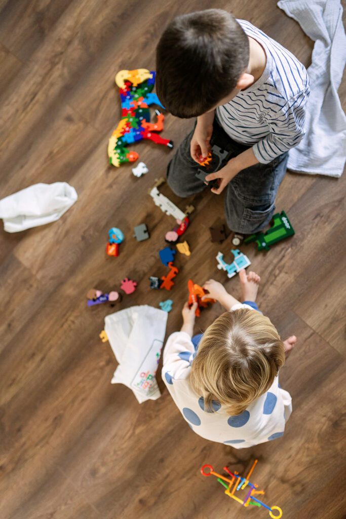 siblings playing with wooden toys at home for natural newborn photography Dublin
