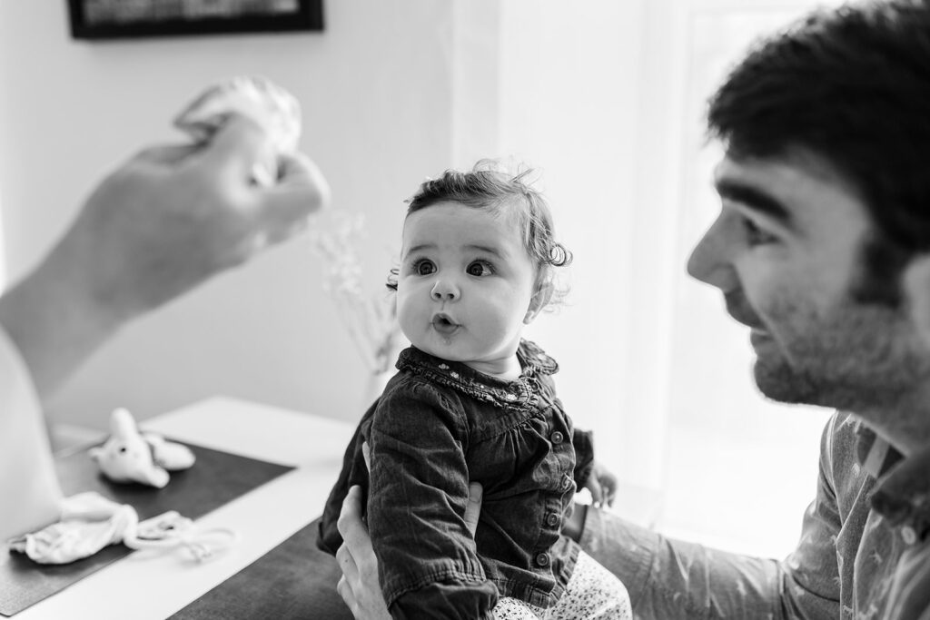 parents entertaining and feeding their baby  during a child-led photography session in Dublin