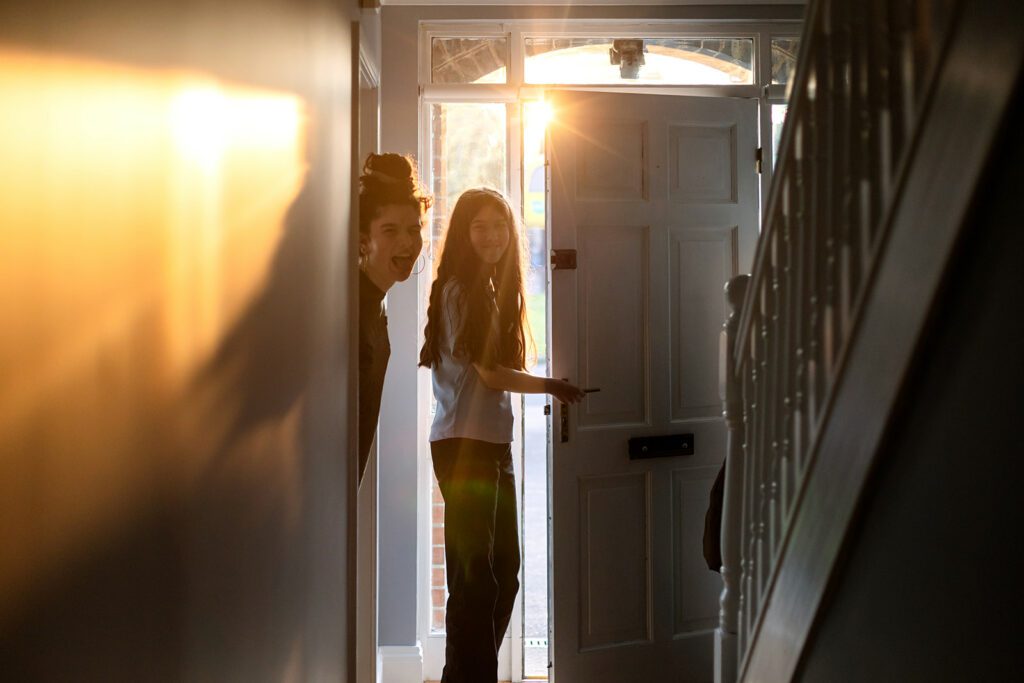 kids smiling and opening the door at home