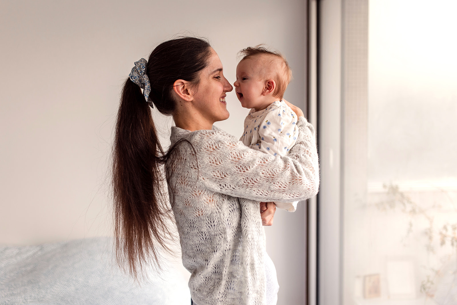 mother playing with baby by the window