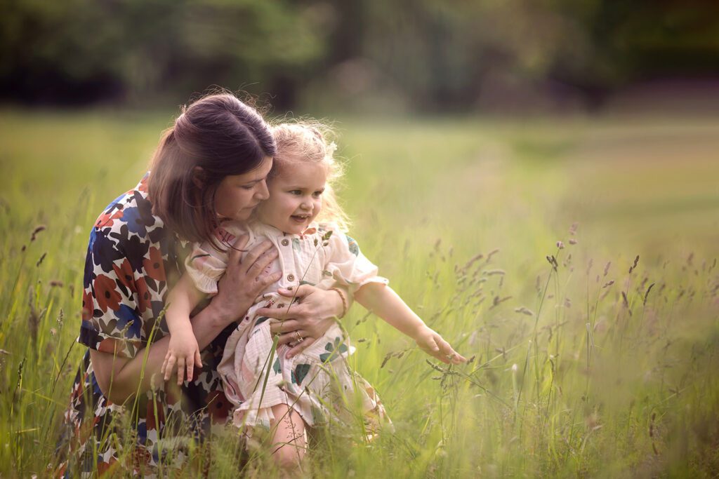 pregnant mum cuddling her toddler girl at the park for a photo session