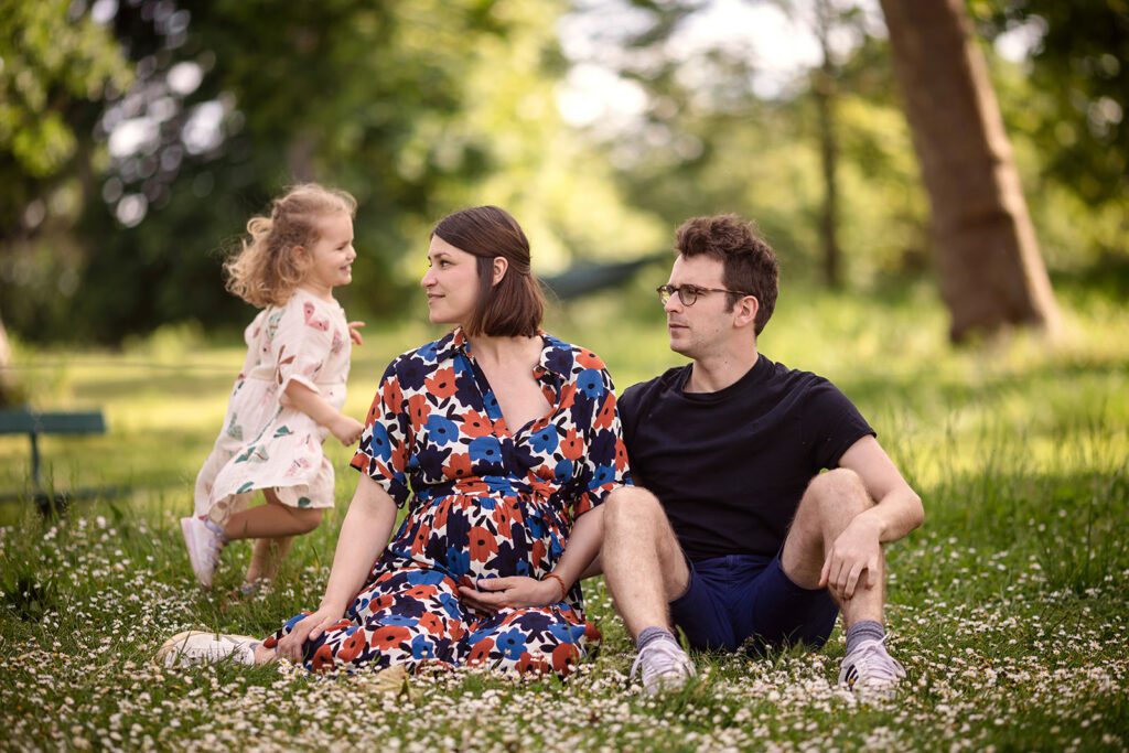 family sitting and playing with toddler outside