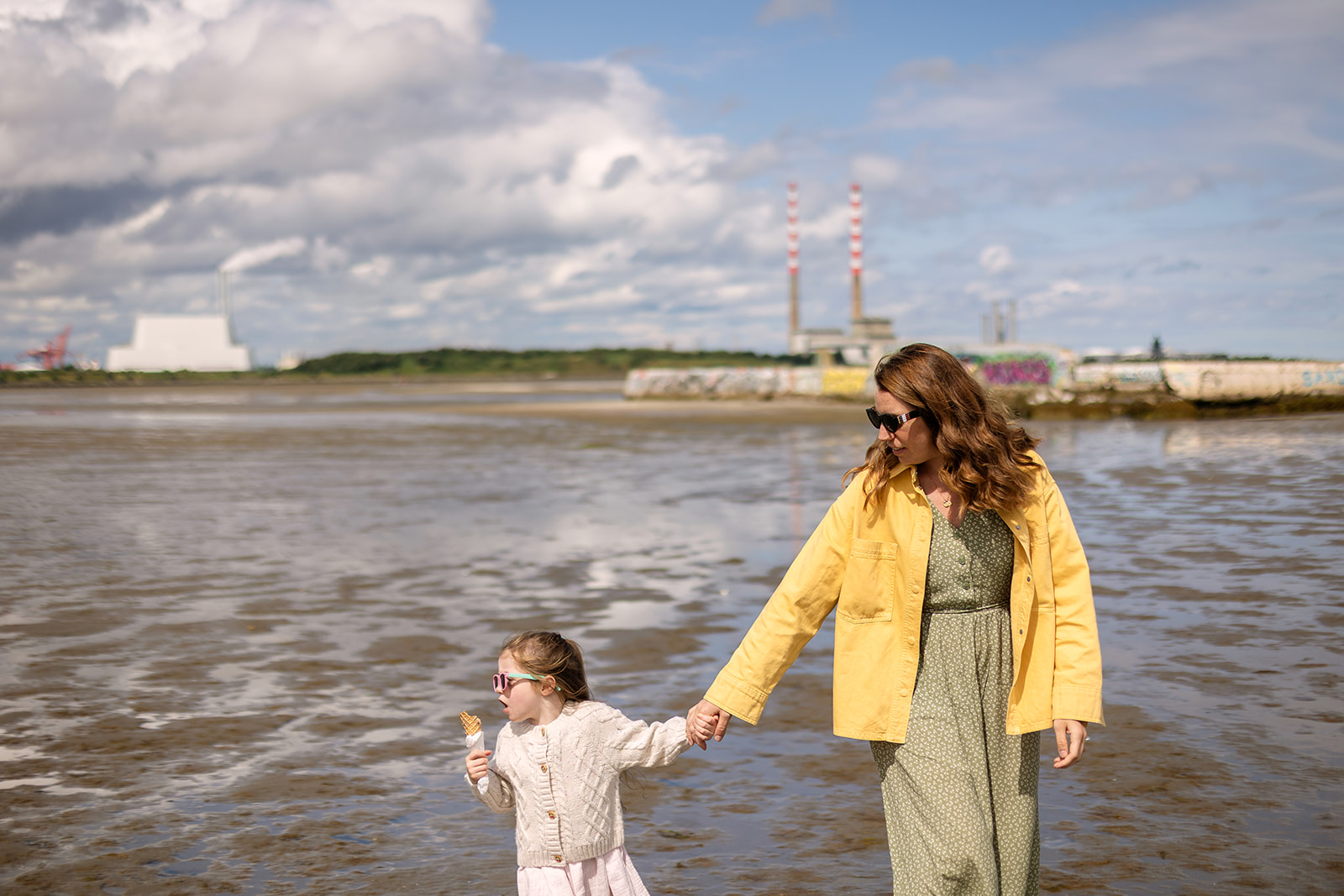 Mother and daughter holding hands in the shallow water at Sandymount Beach
